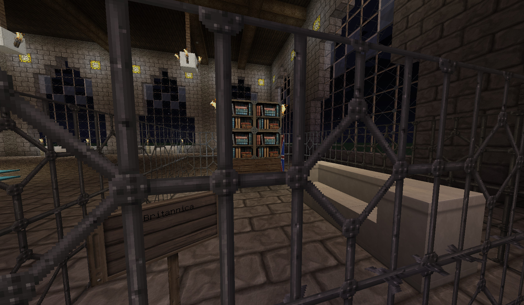 Quatre étagères de livres derrière une grille en fer.